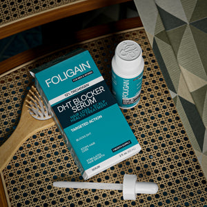 俯視FOLIGAIN DHT精華液包裝盒、瓶子與滴管，旁邊是一把髮梳。