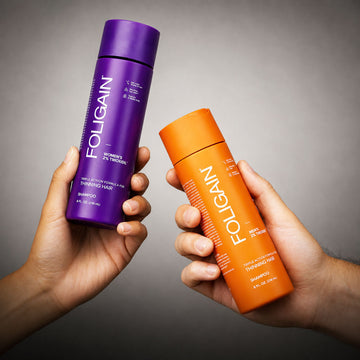 Hands holding women’s and men’s FOLIGAIN TRIOXIDIL shampoo bottles.